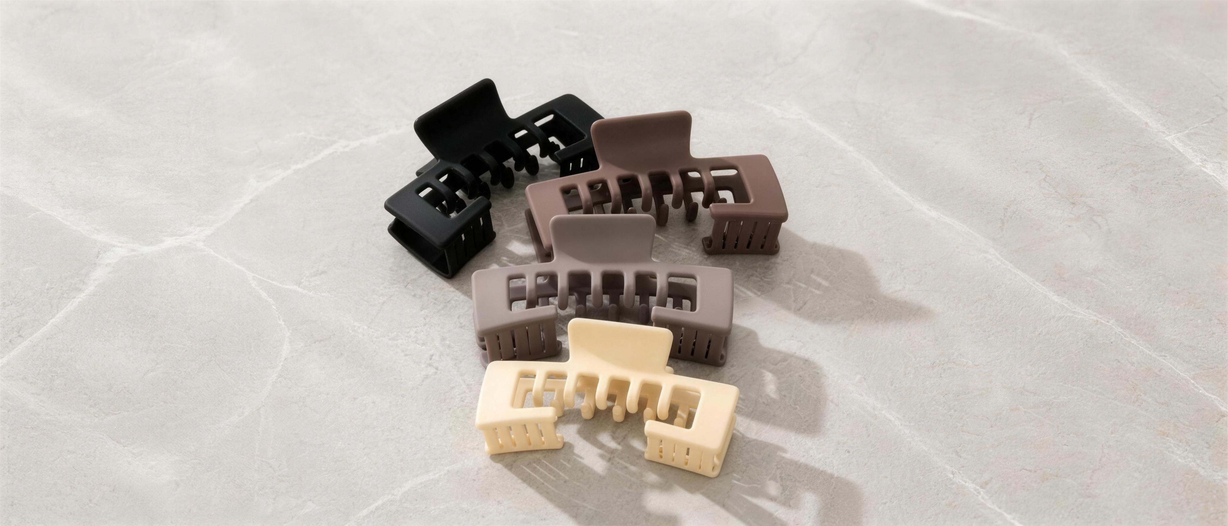 Alora Hat Claw Clips in four matte colors styled on a table