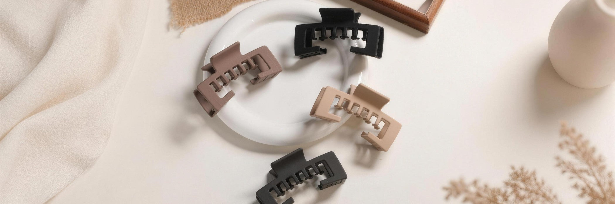 Alora hat claw clips in four matte colors styled on a plate